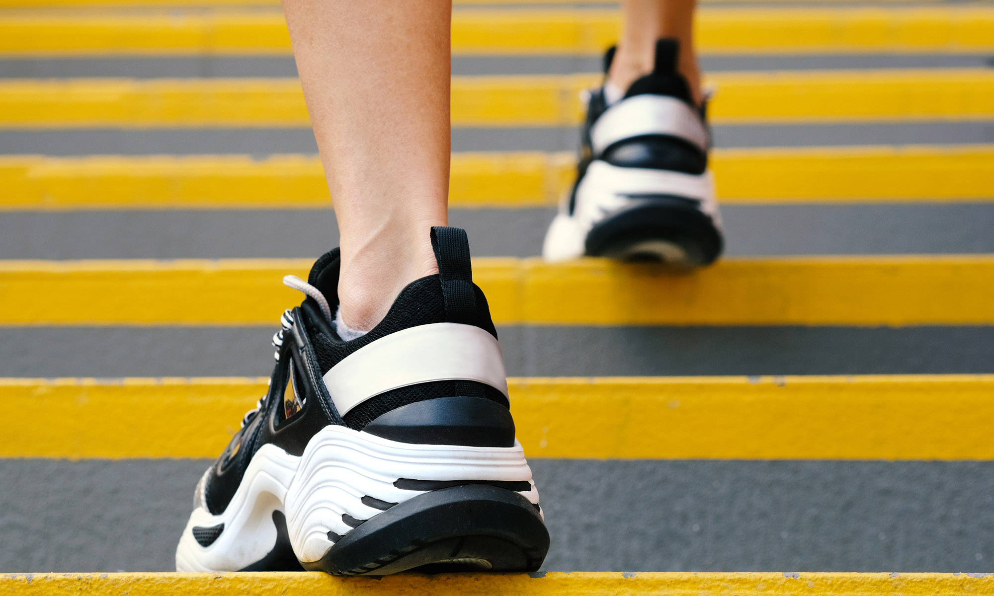 Close-up of sneakers on female legs on the stairs in the stadium, rear view. Female muscular legs in sneakers. Concepts of sport, health and wellness close up of sneakers