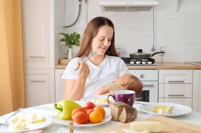 Mother smiles as she feeds her baby while seated table filled with breakfast foods bright warm kitchen fresh fruits bread are neatly arranged freepik
