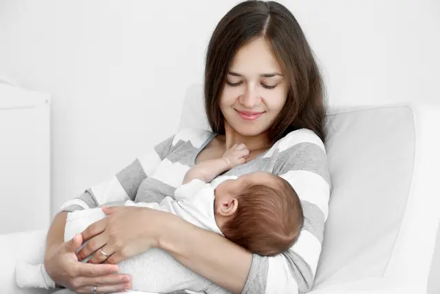 Portrait pretty young woman holding sleeping baby home freepik
